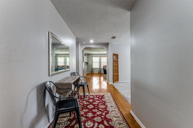 1017 Lake Trail Dr, Little Elm, TX 75068 - corridor featuring arched walkways, wood finished floors, a textured ceiling, baseboards, and a textured wall