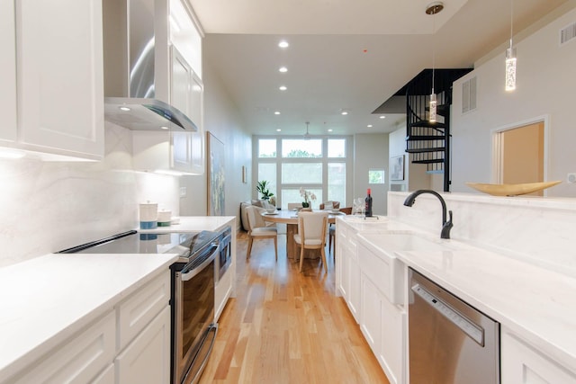 2111 Clark St Unit C, Dallas, TX 75204 - kitchen with stainless steel appliances, wall chimney exhaust hood, light wood-style flooring, recessed lighting, and white cabinets