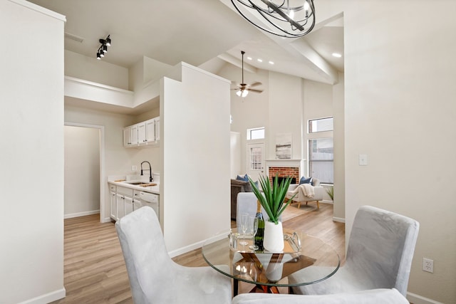 808 Brockden Dr, Mesquite, TX 75149 - dining space featuring baseboards, light wood-style floors, high vaulted ceiling, a brick fireplace, and a ceiling fan