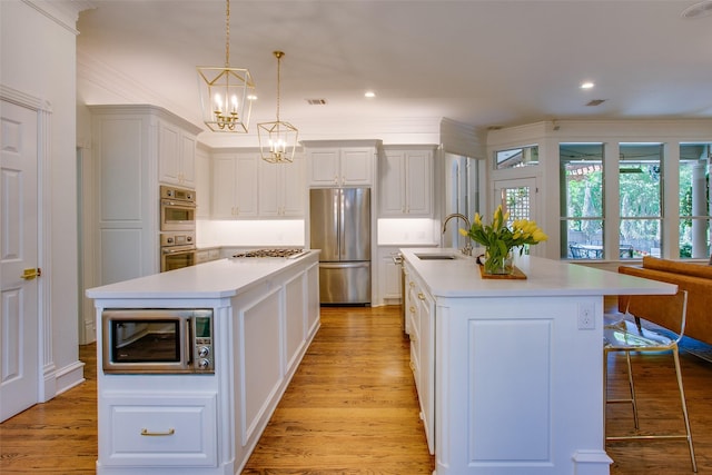 1360 Bent Trail Cir, Southlake, TX 76092 - kitchen featuring appliances with stainless steel finishes, a center island with sink, a chandelier, light countertops, and light wood-style flooring