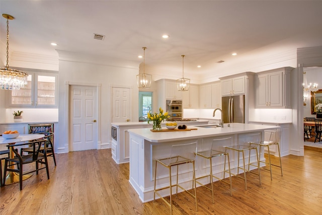 1360 Bent Trail Cir, Southlake, TX 76092 - kitchen with appliances with stainless steel finishes, a chandelier, a large island with sink, light countertops, and crown molding