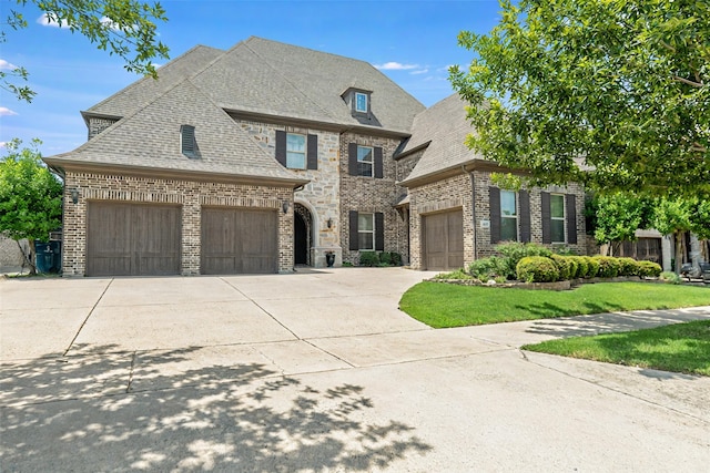 8051 Harliquin Ct, Frisco, TX 75035 - french country style house with brick siding, concrete driveway, an attached garage, a shingled roof, and a front yard