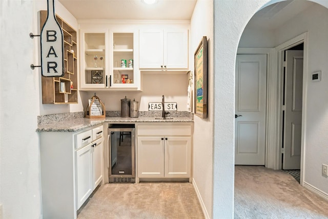 8051 Harliquin Ct, Frisco, TX 75035 - indoor wet bar featuring wine cooler, light carpet, and arched walkways