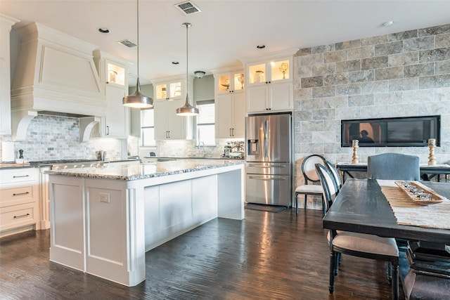 8051 Harliquin Ct, Frisco, TX 75035 - kitchen featuring stainless steel fridge with ice dispenser, glass insert cabinets, premium range hood, a kitchen island, and decorative backsplash