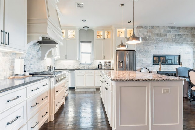 8051 Harliquin Ct, Frisco, TX 75035 - kitchen with appliances with stainless steel finishes, a center island, a sink, glass insert cabinets, and premium range hood