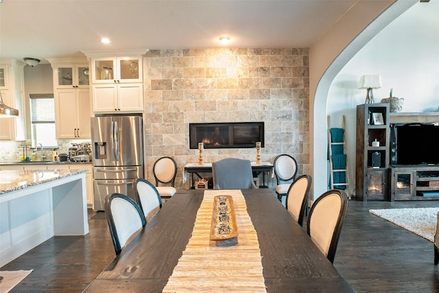 8051 Harliquin Ct, Frisco, TX 75035 - dining area with dark wood-style flooring, a fireplace, arched walkways, and recessed lighting