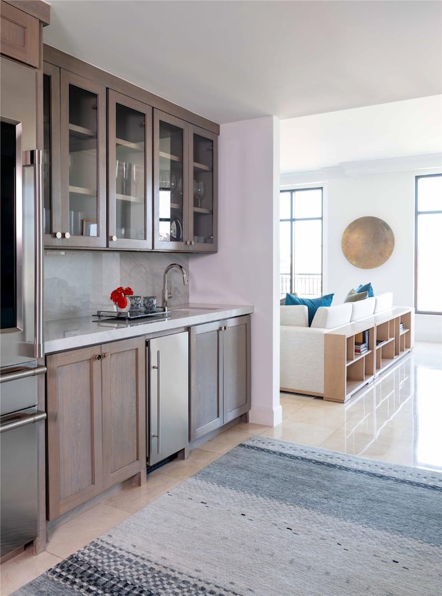 2828 Hood St Unit 1303, Dallas, TX 75219 - indoor wet bar featuring stainless steel refrigerator, healthy amount of natural light, light tile patterned floors, and decorative backsplash