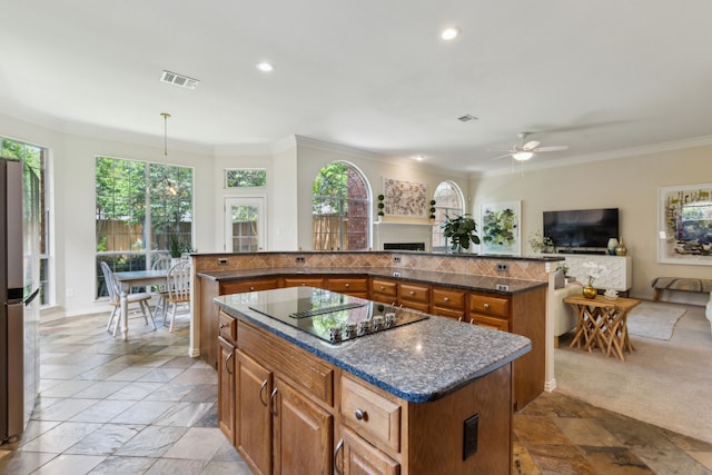 6305 Glenhollow Dr, Plano, TX 75093 - kitchen with a center island, black electric stovetop, brown cabinetry, ceiling fan, and ornamental molding