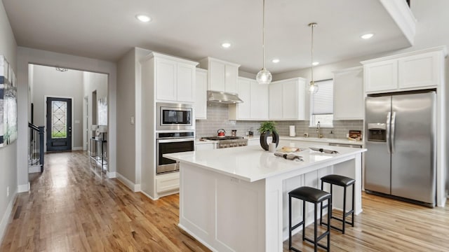 15270 Catalpa Rd, Frisco, TX 75035 - kitchen featuring stainless steel appliances, under cabinet range hood, light wood-style floors, tasteful backsplash, and recessed lighting