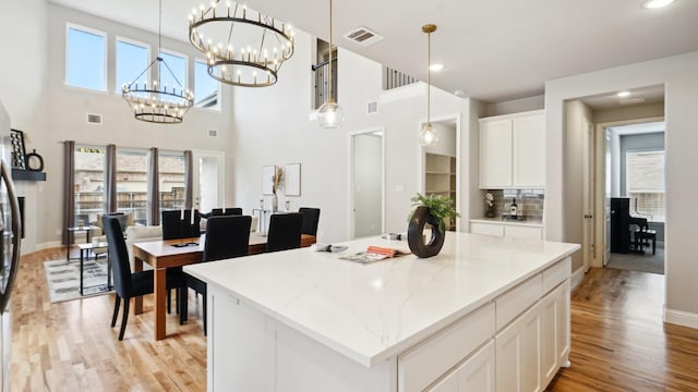 15270 Catalpa Rd, Frisco, TX 75035 - kitchen featuring light wood-style floors, white cabinetry, pendant lighting, a kitchen island, and light stone countertops