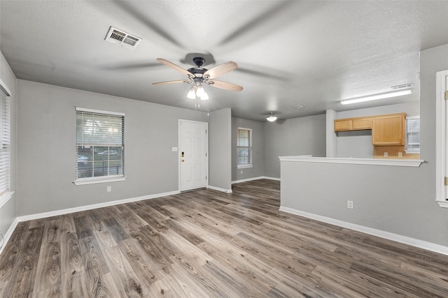 600 Calumet St, Waco, TX 76704 - unfurnished living room featuring healthy amount of natural light, a ceiling fan, wood finished floors, and a textured ceiling
