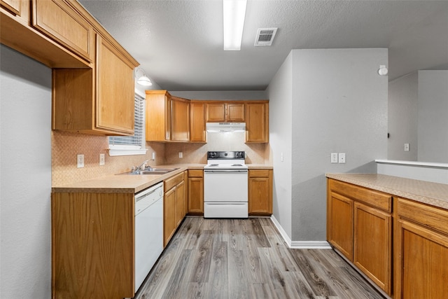 600 Calumet St, Waco, TX 76704 - kitchen with white appliances, under cabinet range hood, a sink, light wood-type flooring, and tasteful backsplash