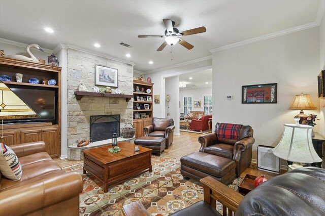 3833 Montecito Dr, Denton, TX 76205 - living area with a ceiling fan, ornamental molding, recessed lighting, a stone fireplace, and light wood-style flooring