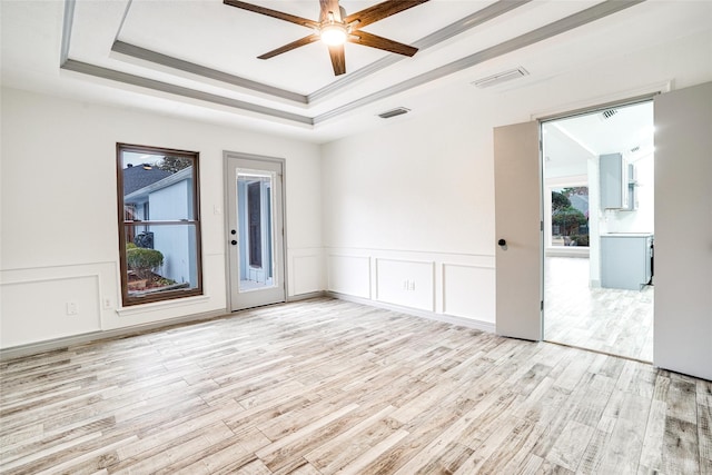 1705 Danube Ln, Plano, TX 75075 - empty room with light wood-style floors, a ceiling fan, a raised ceiling, wainscoting, and a decorative wall