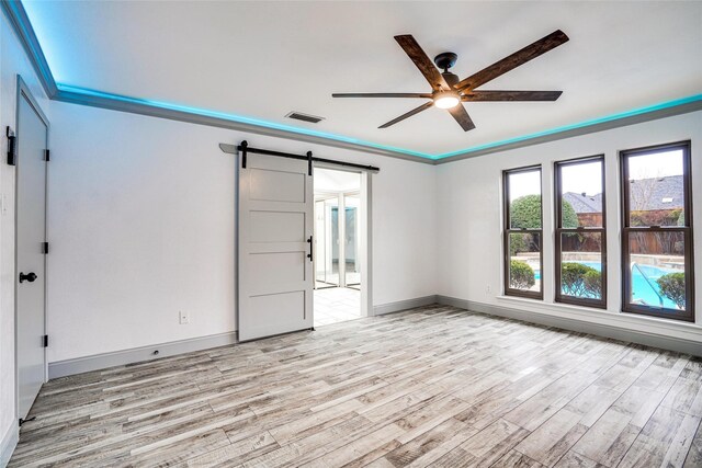 1705 Danube Ln, Plano, TX 75075 - empty room with a barn door, ceiling fan, and light wood-type flooring