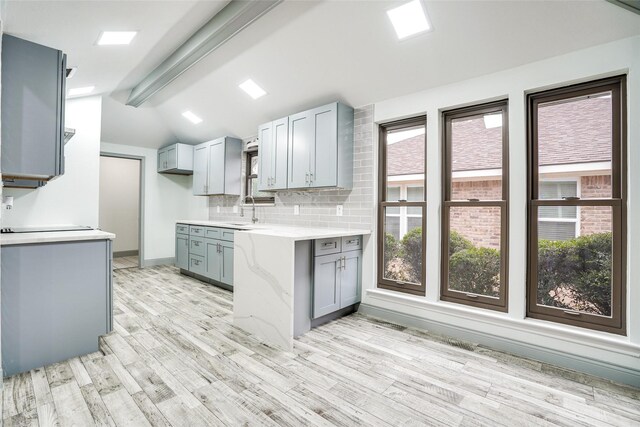 1705 Danube Ln, Plano, TX 75075 - kitchen with gray cabinetry, light wood finished floors, a sink, tasteful backsplash, and baseboards