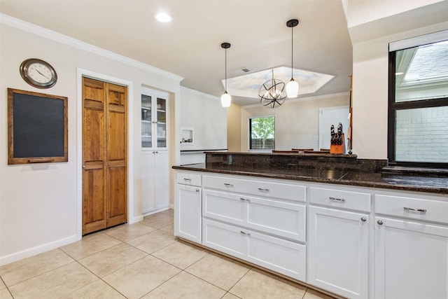 3330 Creekbend Dr, Garland, TX 75044 - kitchen with white cabinetry, crown molding, dark stone countertops, light tile patterned floors, and hanging light fixtures