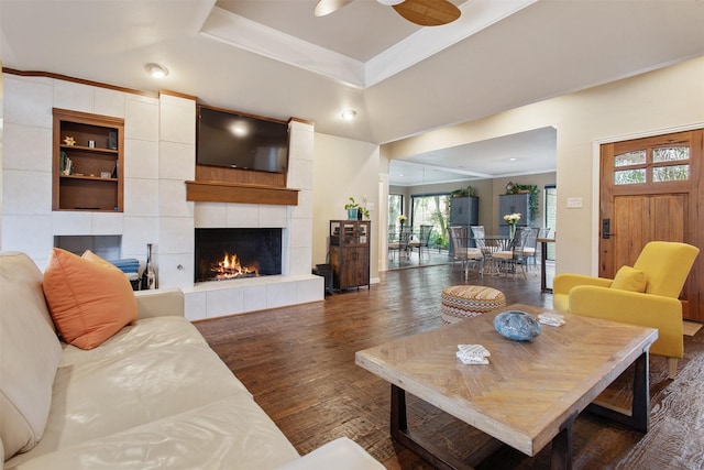 3330 Creekbend Dr, Garland, TX 75044 - living room featuring wood finished floors, a ceiling fan, a tile fireplace, and a tray ceiling