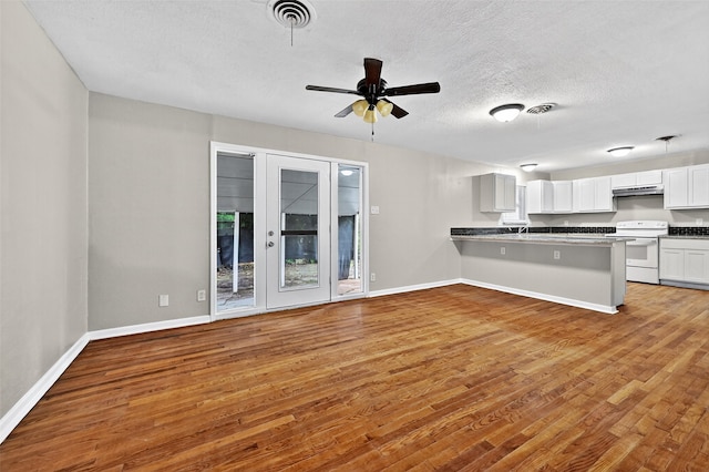 1306 Blanton Pl, Sherman, TX 75092 - kitchen with white range with electric stovetop, under cabinet range hood, wood finished floors, a peninsula, and a textured ceiling