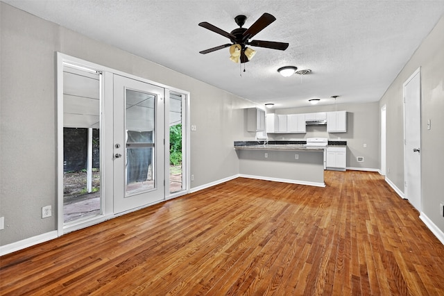1306 Blanton Pl, Sherman, TX 75092 - kitchen with wood finished floors, a textured ceiling, a peninsula, white cabinetry, and under cabinet range hood