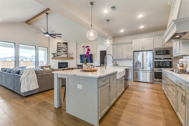 3109 Twin Eagles Dr, Celina, TX 75009 - kitchen with stainless steel appliances, custom range hood, gray cabinets, a glass covered fireplace, and a sink