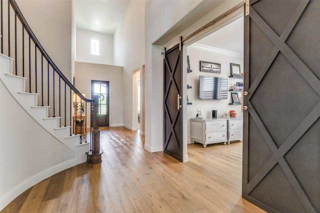 3109 Twin Eagles Dr, Celina, TX 75009 - entryway with a barn door, baseboards, light wood-style floors, stairs, and a high ceiling