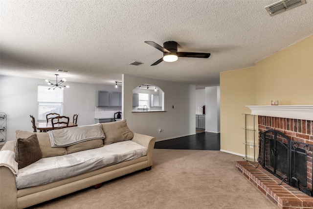 5504 Cedar Mountain Dr, Mckinney, TX 75071 - living room featuring a chandelier, a ceiling fan, carpet floors, a brick fireplace, and a textured ceiling