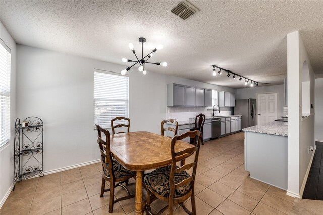 5504 Cedar Mountain Dr, Mckinney, TX 75071 - dining room featuring a chandelier, healthy amount of natural light, light tile patterned floors, a textured ceiling, and rail lighting