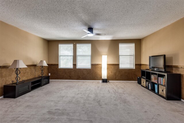5504 Cedar Mountain Dr, Mckinney, TX 75071 - unfurnished living room featuring wainscoting, plenty of natural light, ceiling fan, carpet flooring, and a textured ceiling