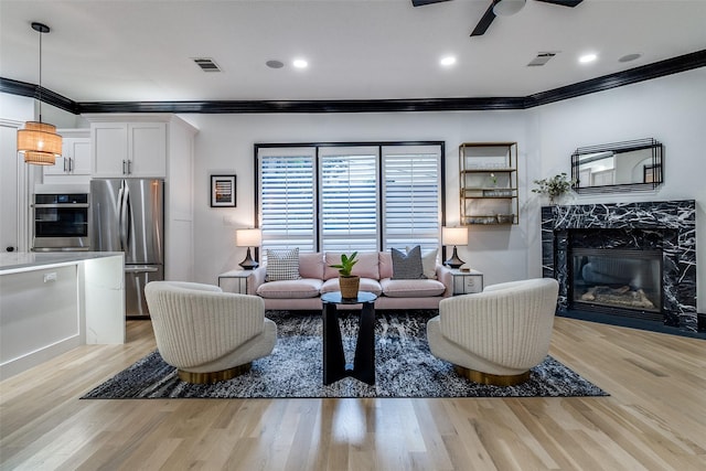 4518 Gilbert Ave, Dallas, TX 75219 - living area with crown molding, a premium fireplace, a ceiling fan, light wood-type flooring, and recessed lighting