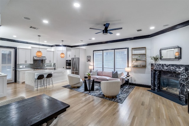 4518 Gilbert Ave, Dallas, TX 75219 - living area with ceiling fan, ornamental molding, light wood finished floors, a fireplace, and recessed lighting