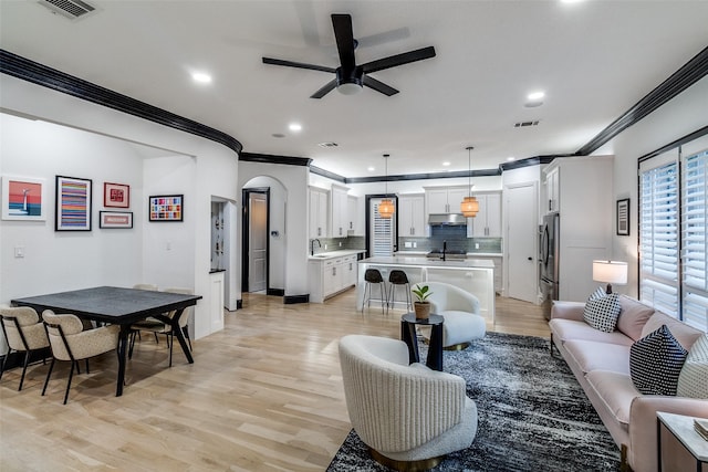 4518 Gilbert Ave, Dallas, TX 75219 - living area featuring crown molding, ceiling fan, light wood-style flooring, recessed lighting, and arched walkways