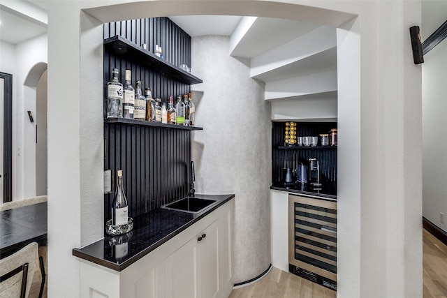 4518 Gilbert Ave, Dallas, TX 75219 - indoor wet bar featuring beverage cooler, arched walkways, and light wood-style flooring