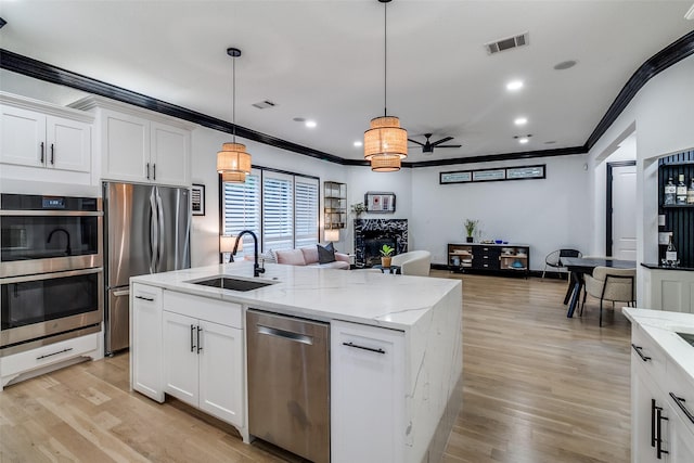 4518 Gilbert Ave, Dallas, TX 75219 - kitchen featuring appliances with stainless steel finishes, a sink, ornamental molding, open floor plan, and light wood-type flooring