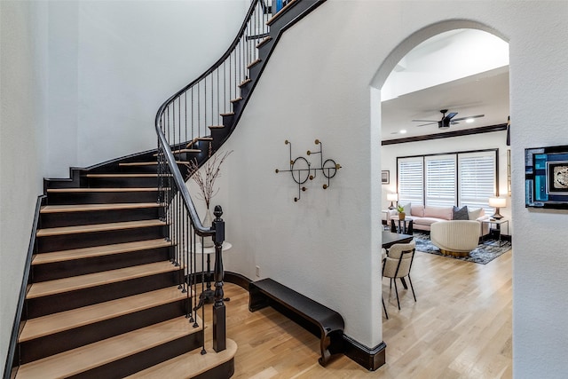 4518 Gilbert Ave, Dallas, TX 75219 - staircase with ceiling fan, wood finished floors, arched walkways, and crown molding
