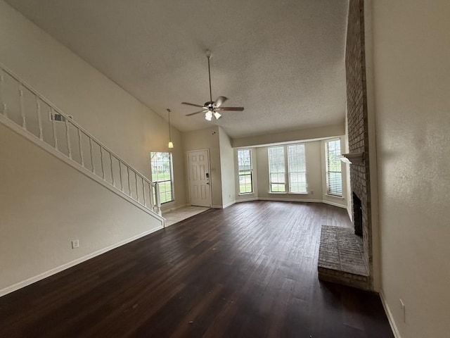 413 Creekwood Ln, Lewisville, TX 75067 - unfurnished living room with wood finished floors, baseboards, a ceiling fan, a textured ceiling, and a brick fireplace