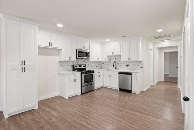 717 W Boyce Ave, Fort Worth, TX 76115 - kitchen featuring appliances with stainless steel finishes, a sink, light countertops, white cabinets, and decorative backsplash