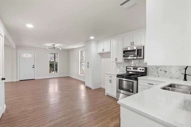 717 W Boyce Ave, Fort Worth, TX 76115 - kitchen featuring stainless steel appliances, a sink, light wood finished floors, backsplash, and a chandelier