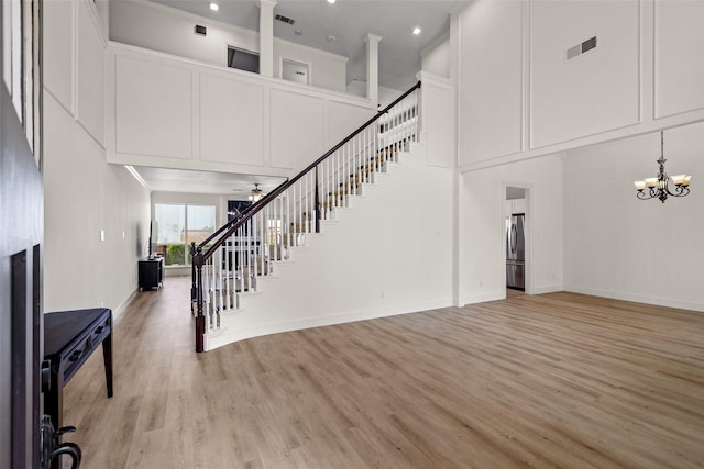 3936 Gillespie Dr, Carrollton, TX 75010 - unfurnished living room with stairs, light wood-style flooring, a chandelier, recessed lighting, and a towering ceiling