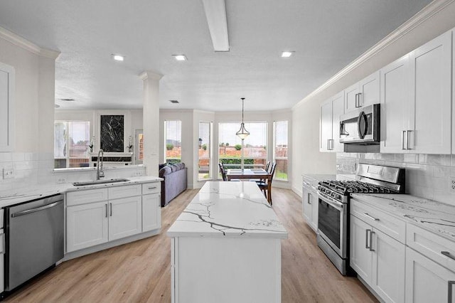 3936 Gillespie Dr, Carrollton, TX 75010 - kitchen with appliances with stainless steel finishes, a sink, crown molding, plenty of natural light, and light wood finished floors