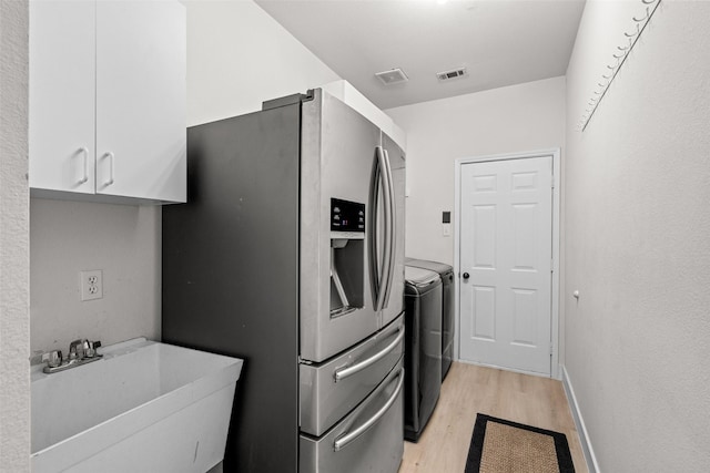 3936 Gillespie Dr, Carrollton, TX 75010 - kitchen with a sink, stainless steel fridge, light wood-style flooring, washer and clothes dryer, and white cabinets