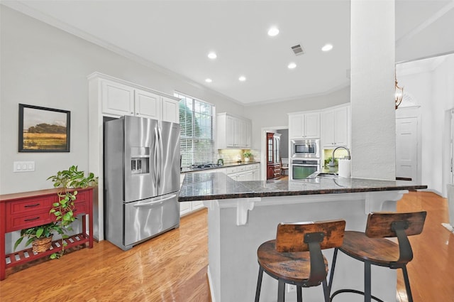 1403 Chelsea Cir, Southlake, TX 76092 - kitchen featuring stainless steel appliances, a kitchen bar, crown molding, light wood-style flooring, and white cabinetry