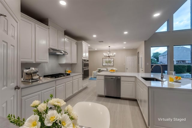 14548 Blakehill Dr, Frisco, TX 75035 - kitchen featuring appliances with stainless steel finishes, a sink, under cabinet range hood, a chandelier, and recessed lighting