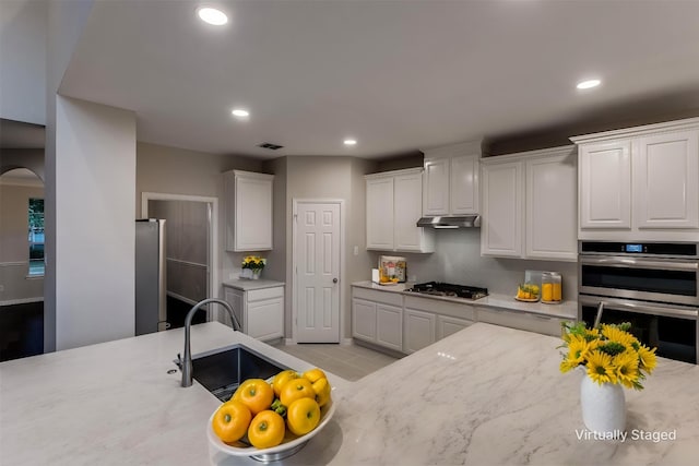 14548 Blakehill Dr, Frisco, TX 75035 - kitchen with stainless steel appliances, a sink, recessed lighting, white cabinets, and arched walkways