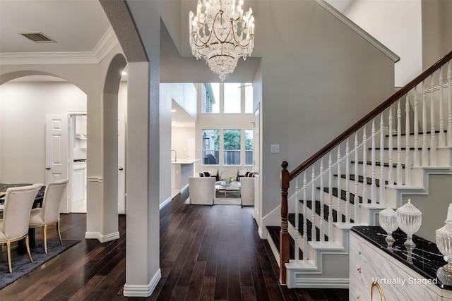 14548 Blakehill Dr, Frisco, TX 75035 - foyer entrance with arched walkways, dark wood-type flooring, a chandelier, stairway, and crown molding
