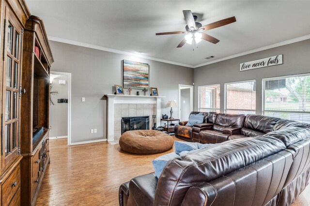 4811 Jakes Way, Midlothian, TX 76065 - living area featuring light wood finished floors, a ceiling fan, crown molding, a tiled fireplace, and baseboards