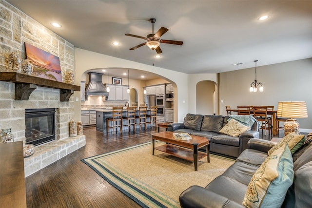 5014 Toledo Bend Dr, Frisco, TX 75033 - living room featuring arched walkways, ceiling fan, a fireplace, dark wood-style floors, and a chandelier