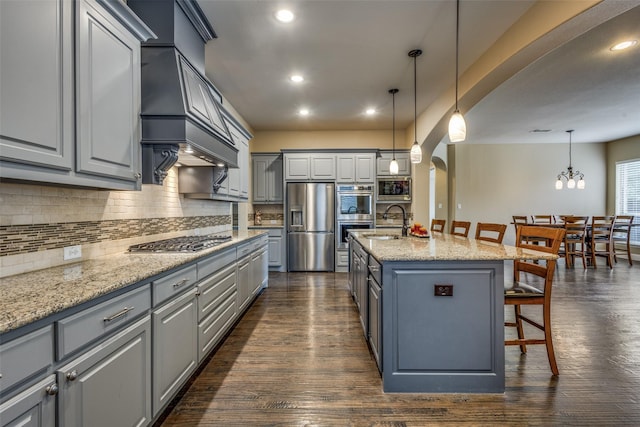 5014 Toledo Bend Dr, Frisco, TX 75033 - kitchen with stainless steel appliances, gray cabinetry, a kitchen breakfast bar, arched walkways, and decorative backsplash