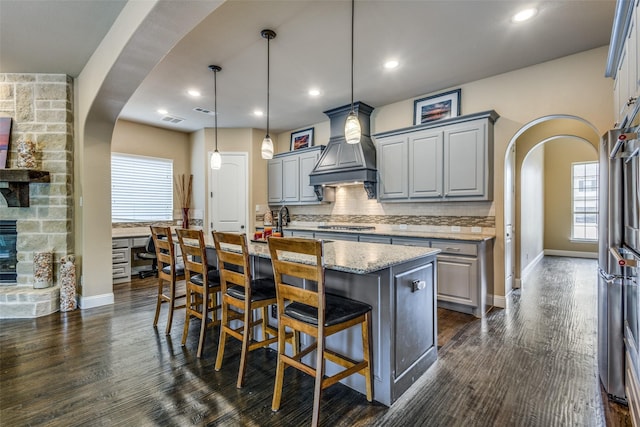 5014 Toledo Bend Dr, Frisco, TX 75033 - kitchen featuring arched walkways, gray cabinetry, custom exhaust hood, backsplash, and a stone fireplace