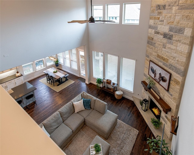 2624 Seabiscuit Rd, Celina, TX 75009 - living area featuring a ceiling fan, a fireplace, a towering ceiling, baseboards, and wood finished floors
